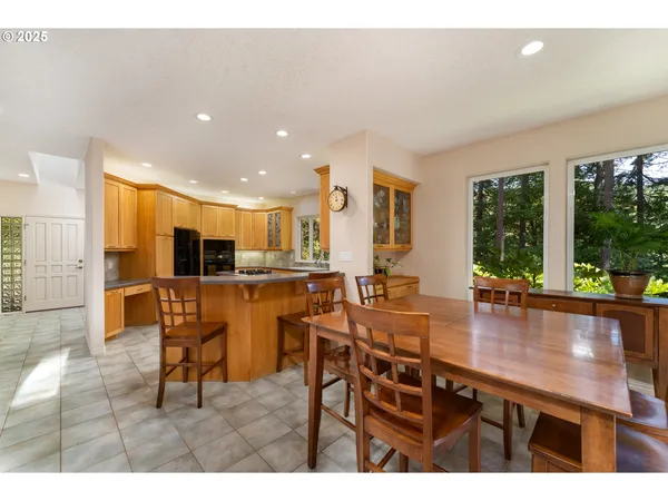 a kitchen with stainless steel appliances kitchen island granite countertop a table chairs and a living room view