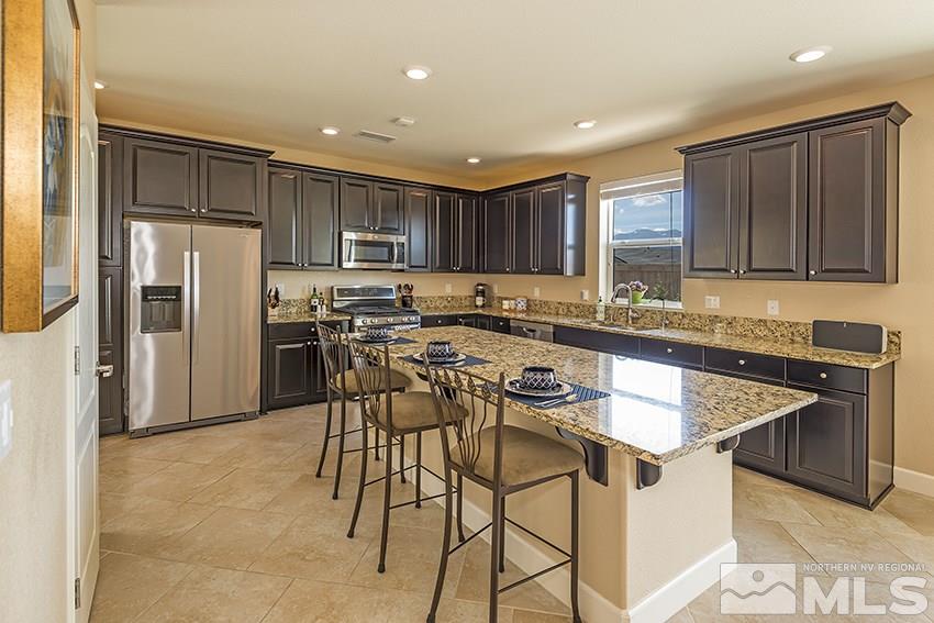 10171 Quintana Drive Reno, NV 89521 - Photo 8 of 25 a kitchen with kitchen island granite countertop wooden cabinets and refrigerator