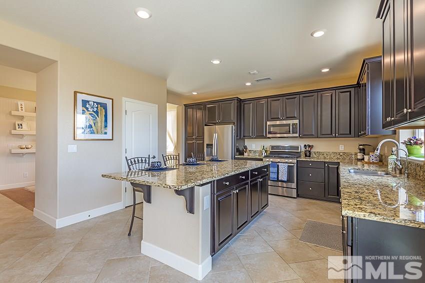 10171 Quintana Drive Reno, NV 89521 - Photo 9 of 25 a kitchen with stainless steel appliances granite countertop a stove top oven a sink dishwasher and a refrigerator