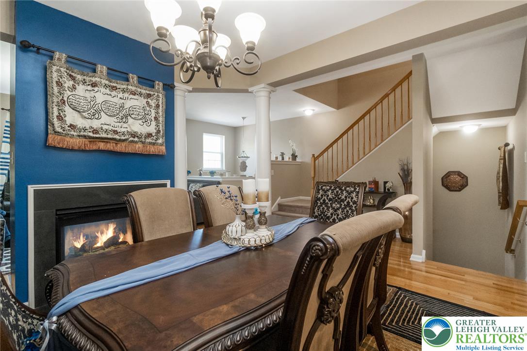 3566 Penfield Way Nazareth, PA 18064 - Photo 19 of 47 An inviting dining area features a warm 2 sided fireplace and rich wood flooring, perfect for memorable gatherings.