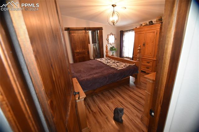 9990 Hahn Road Calhan, CO 80808 - Photo 10 of 25 Bedroom with a chandelier and wood-type flooring