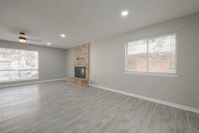 a view of an empty room with a window and wooden floor
