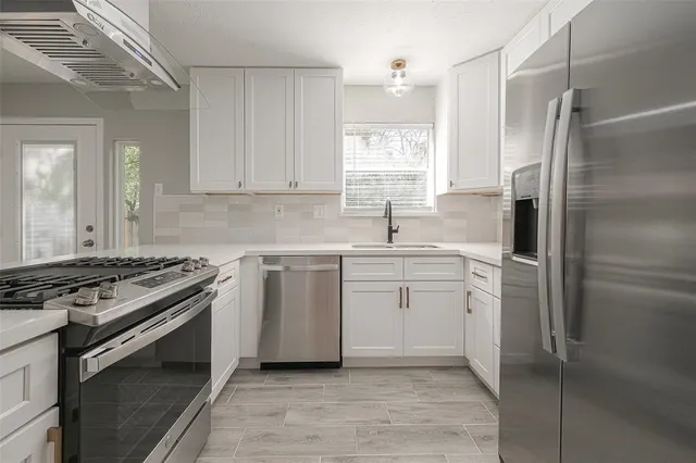 a kitchen with white cabinets and appliances