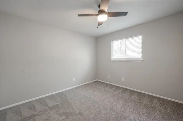 an empty room with a chandelier fan and windows