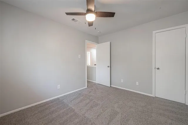 a view of an empty room and chandelier fan