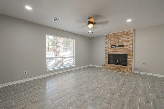 an empty room with wooden floor fireplace and windows