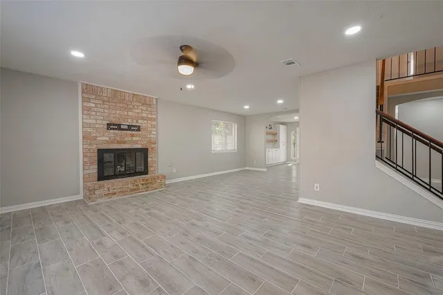 an empty room with wooden floor fireplace and windows