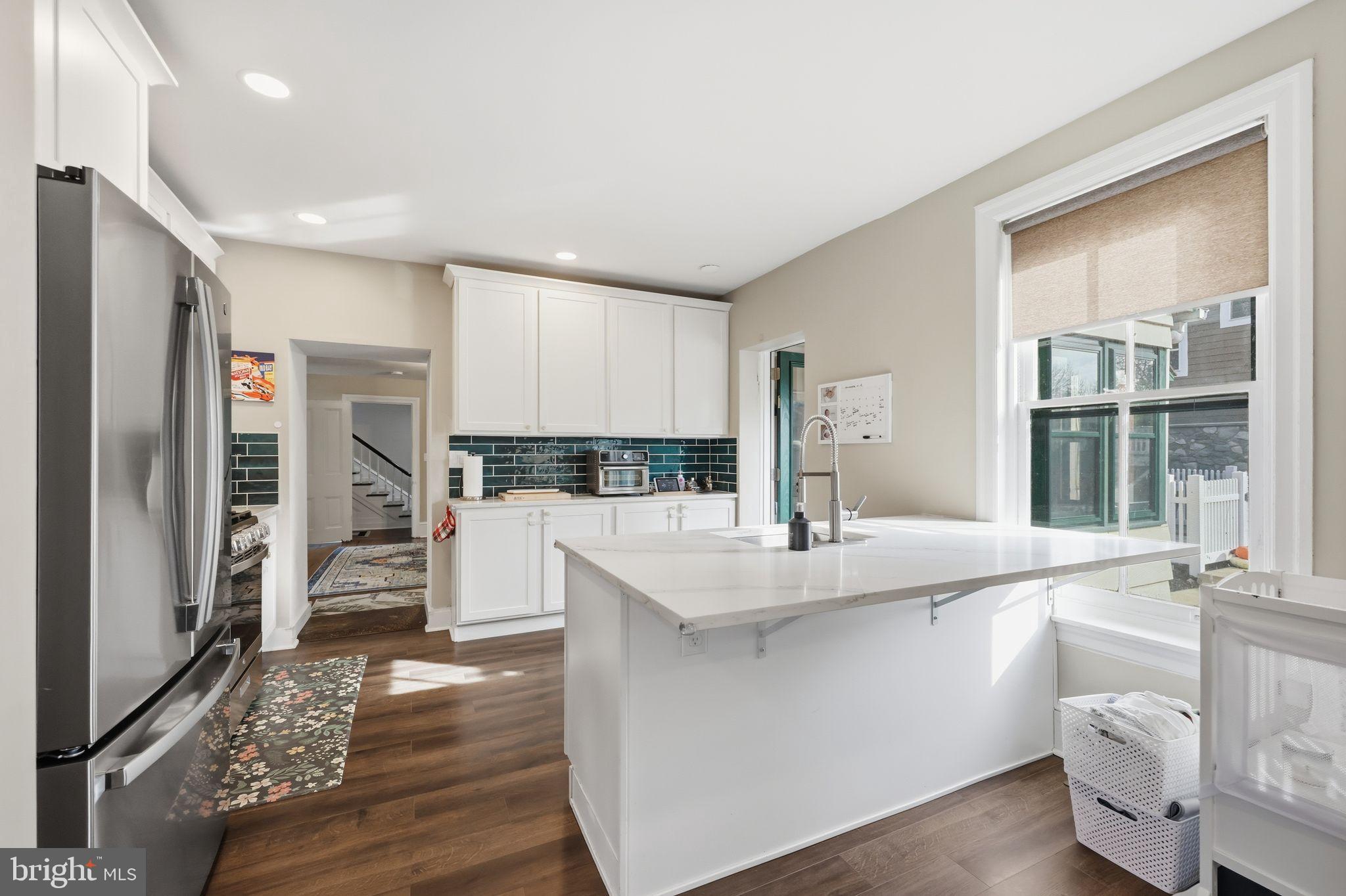 126 North Providence Road Media, PA 19063 - Photo 4 of 28 a large kitchen with kitchen island a stove a sink a refrigerator and white cabinets with wooden floor