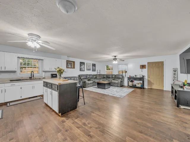 a large white open kitchen with cabinets a sink and dishwasher a stove with wooden floor