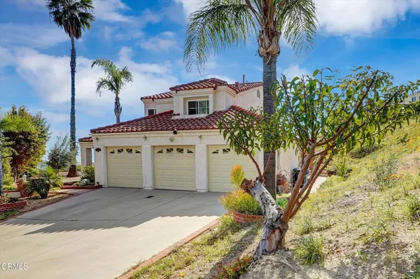 a view of a house with a yard and palm trees