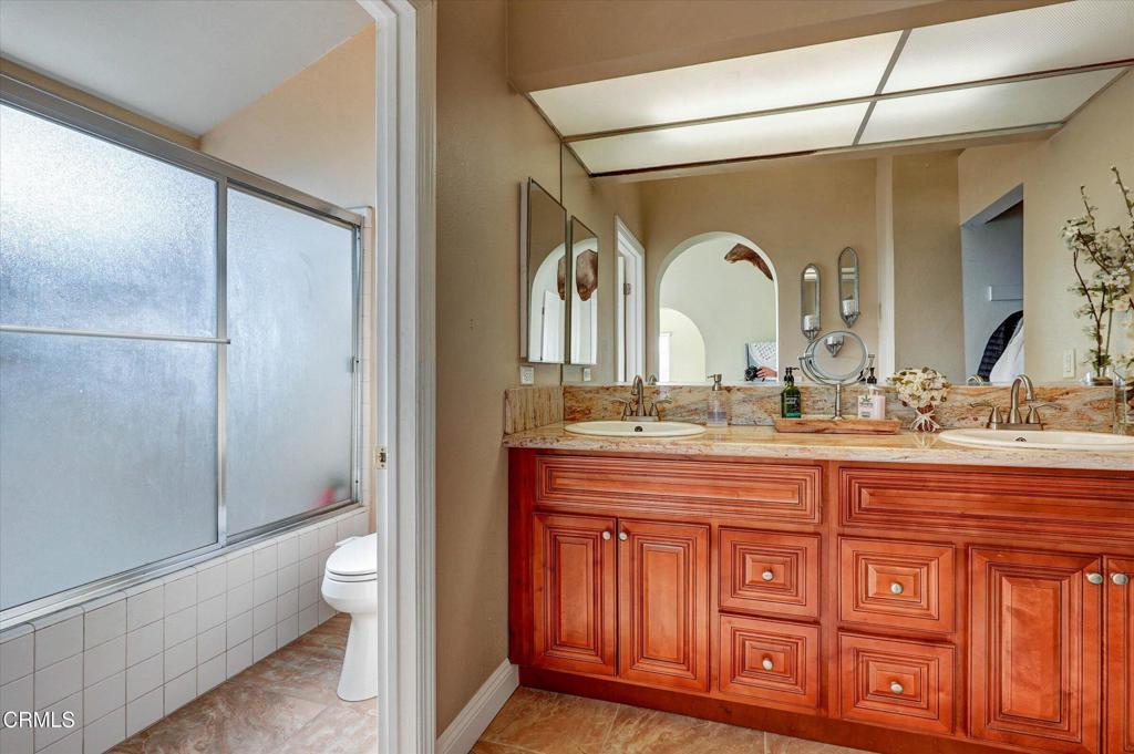 12477 Rajah Street Los Angeles, CA 91342 - Photo 26 of 34 a bathroom with a granite countertop sink a toilet and a shower