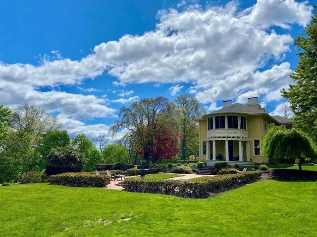 a front view of a house with garden and trees