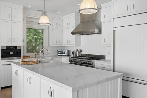 a kitchen with stainless steel appliances granite countertop a stove a sink and a white cabinets