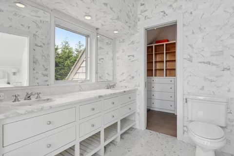 a bathroom with a granite countertop toilet sink and mirror