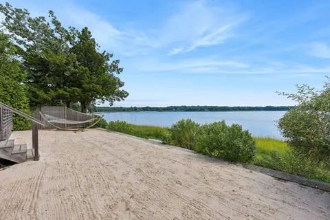 a view of a lake with a yard and large trees