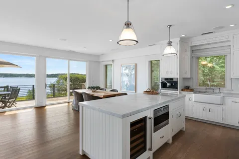 a kitchen with a stove a sink a center island with wooden floor and cabinets