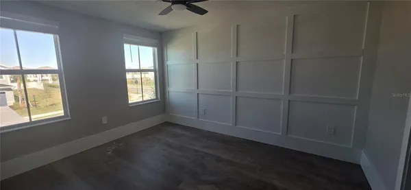 an empty room with wooden floor closet and windows