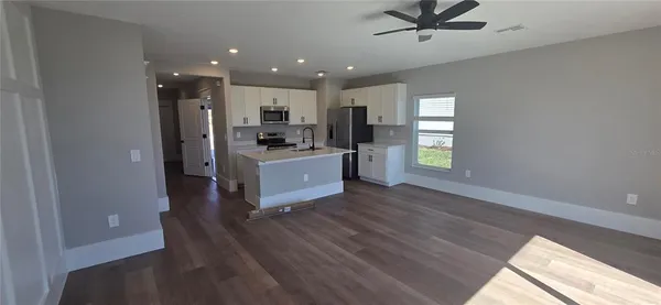 a living room with stainless steel appliances kitchen island hardwood floor and a window