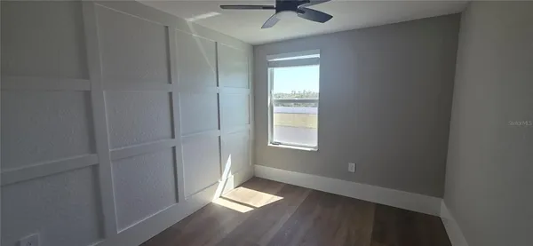 an empty room with a window and a ceiling fan