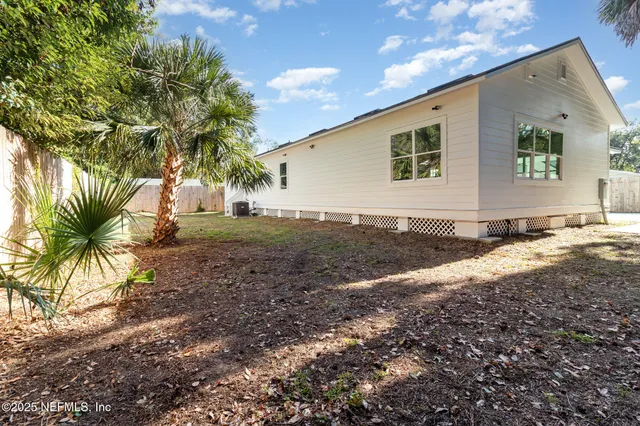a view of a backyard with plants and large tree