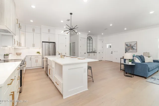a large white kitchen with cabinets a sink and a stove