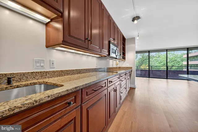a kitchen with stainless steel appliances granite countertop a sink a stove and a wooden floors