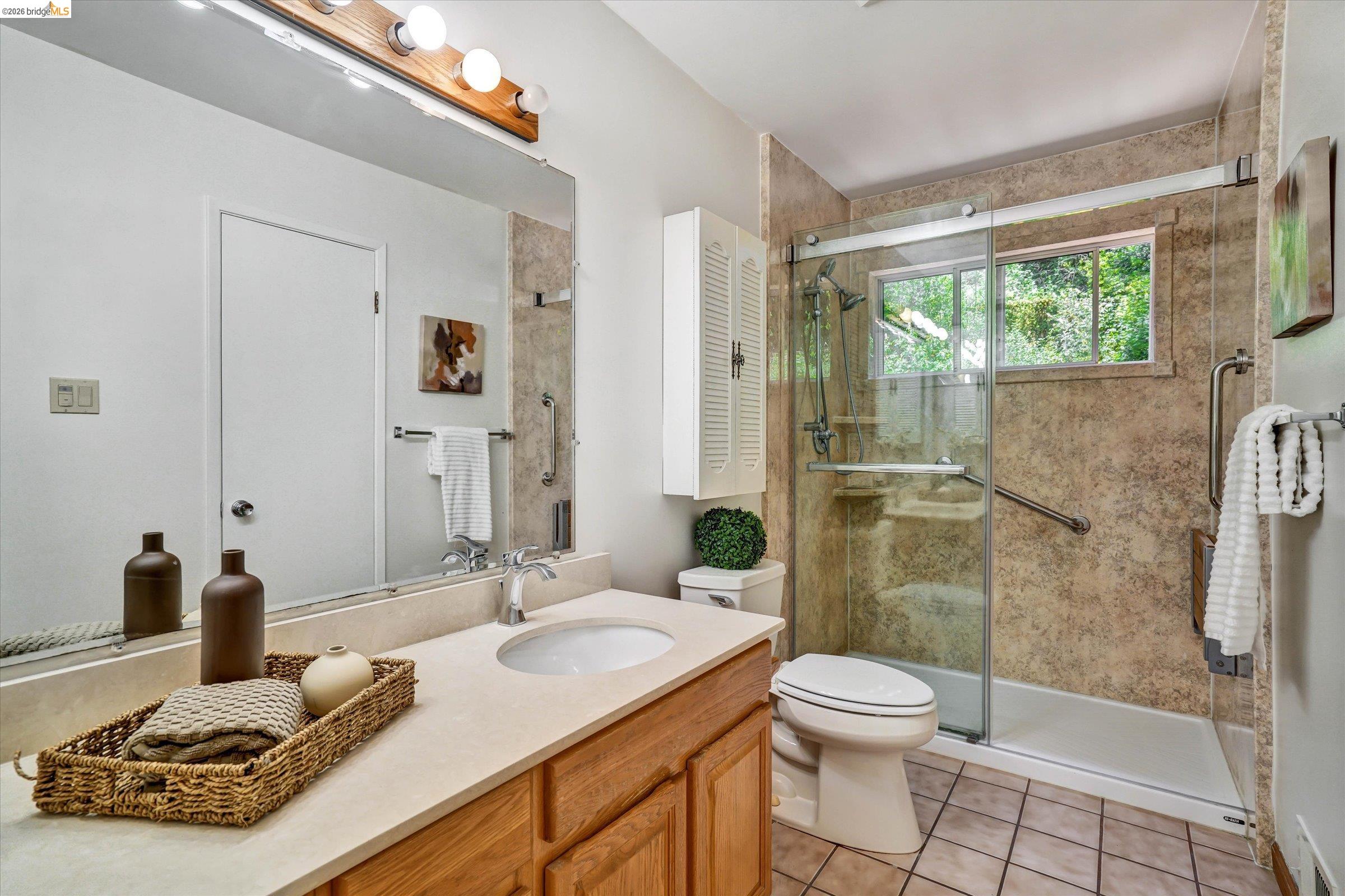 2826 Wright Avenue Pinole, CA 94564 - Photo 47 of 70 Bathroom featuring a single vanity with an integrated sink, a glass-enclosed shower with textured tile surround, a built-in storage cabinet, and tiled flooring