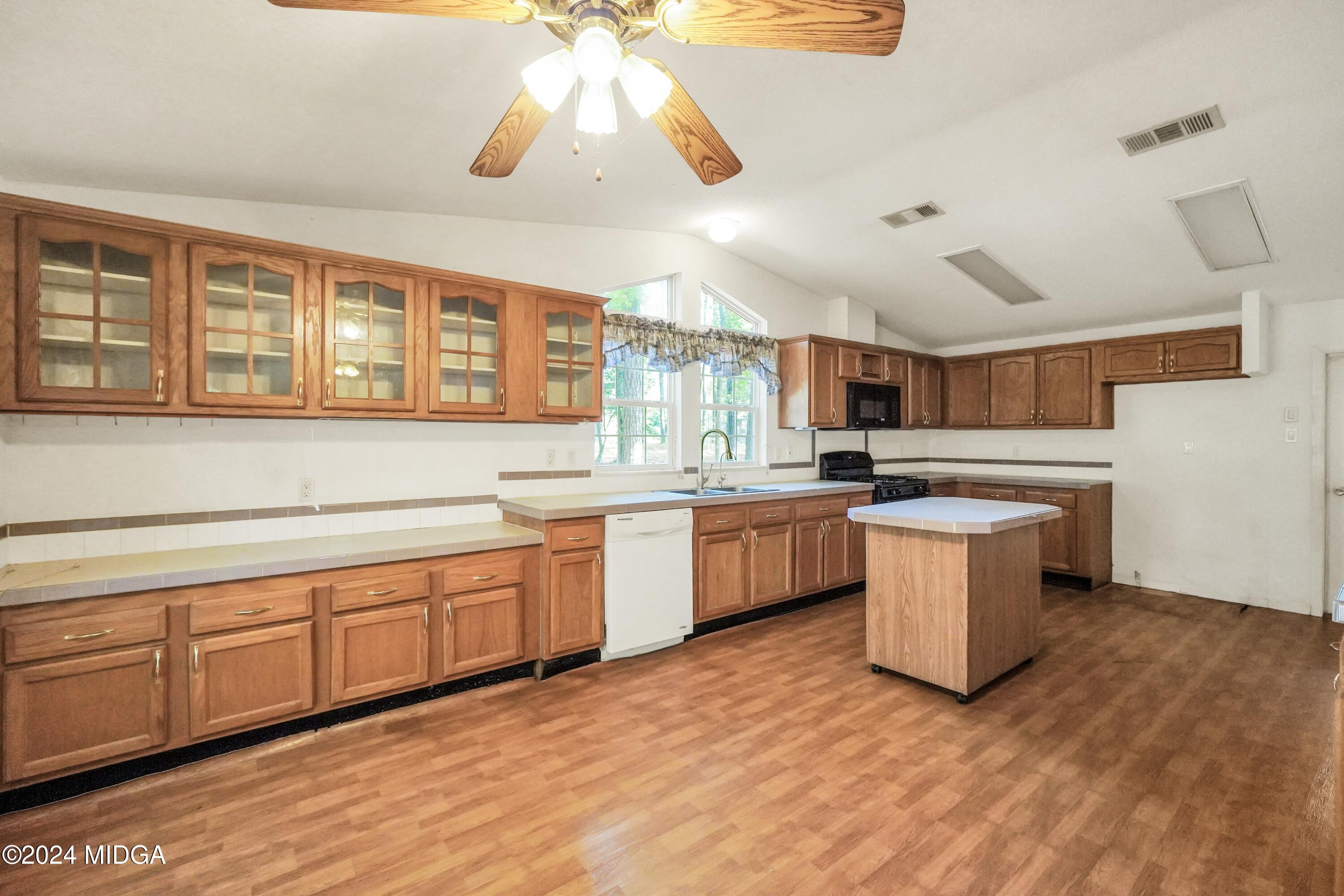 615 Fuller Road Culloden, GA 31016 - Photo 9 of 37 a large kitchen with kitchen island a large counter space a sink stainless steel appliances and cabinets