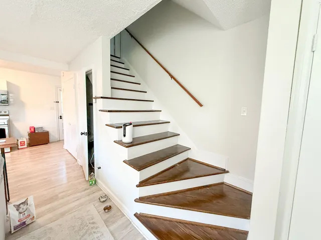 a view of a hallway with wooden floor and staircase
