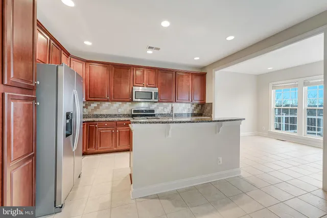 a kitchen with granite countertop wooden cabinets a refrigerator and a sink