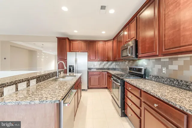 a kitchen with stainless steel appliances granite countertop a stove a sink and a refrigerator
