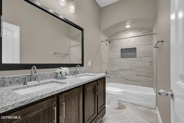 a bathroom with a granite countertop sink a toilet and shower