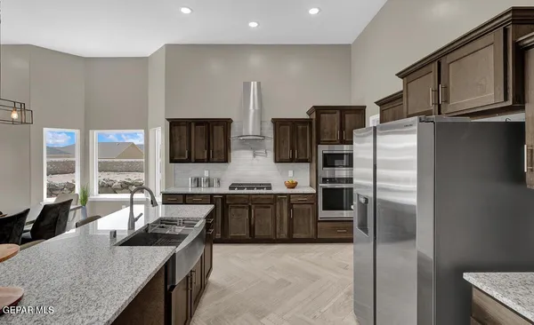 a kitchen with stainless steel appliances granite countertop a refrigerator a stove a sink and a microwave