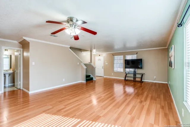 a view of empty room with wooden floor and fan