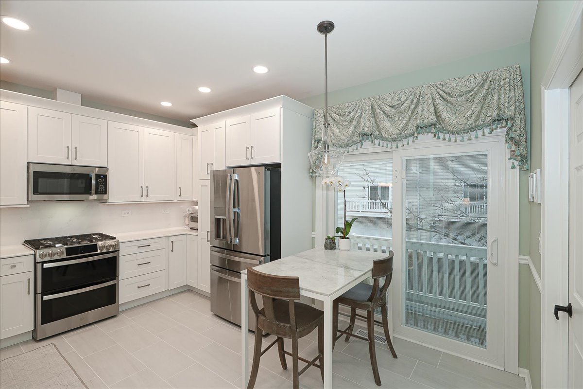 3481 Ravinia Circle Aurora, IL 60504 - Photo 9 of 28 a kitchen with a table chairs refrigerator and microwave