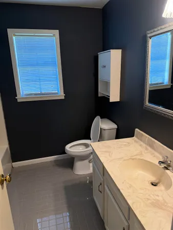 a bathroom with a granite countertop sink a mirror and a toilet