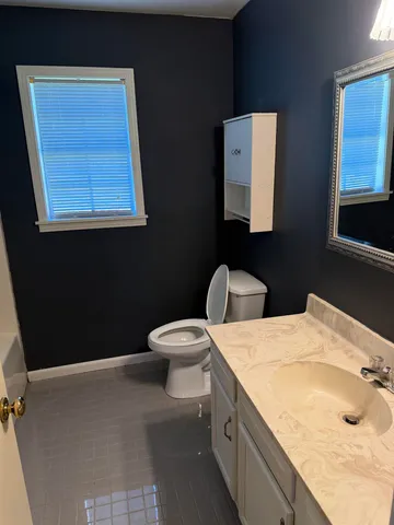a bathroom with a granite countertop sink a mirror and a toilet
