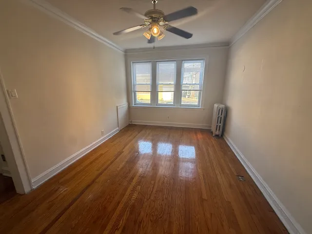 an empty room with wooden floor a ceiling fan and windows