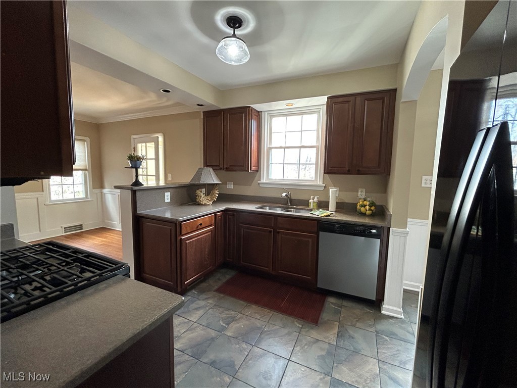 3589 Strandhill Road Beachwood, OH 44122 - Photo 17 of 23 Kitchen with wainscoting, black appliances, healthy amount of natural light, a decorative wall, and ornamental molding