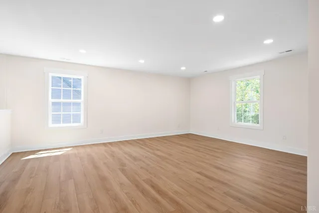an empty room with wooden floor and window
