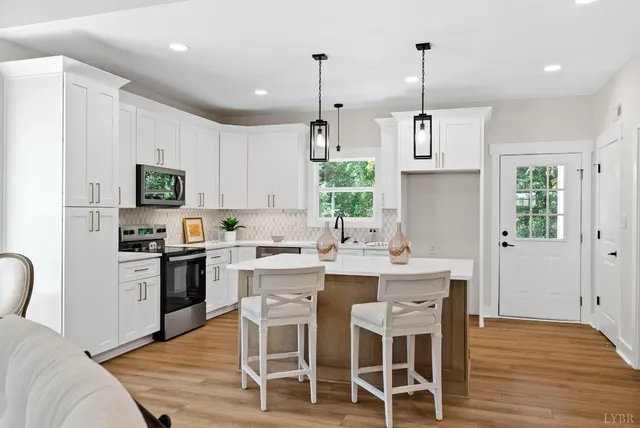 a kitchen with stainless steel appliances a dining table chairs stove refrigerator and microwave