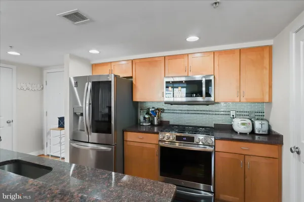 a kitchen with stainless steel appliances granite countertop a refrigerator stove and sink