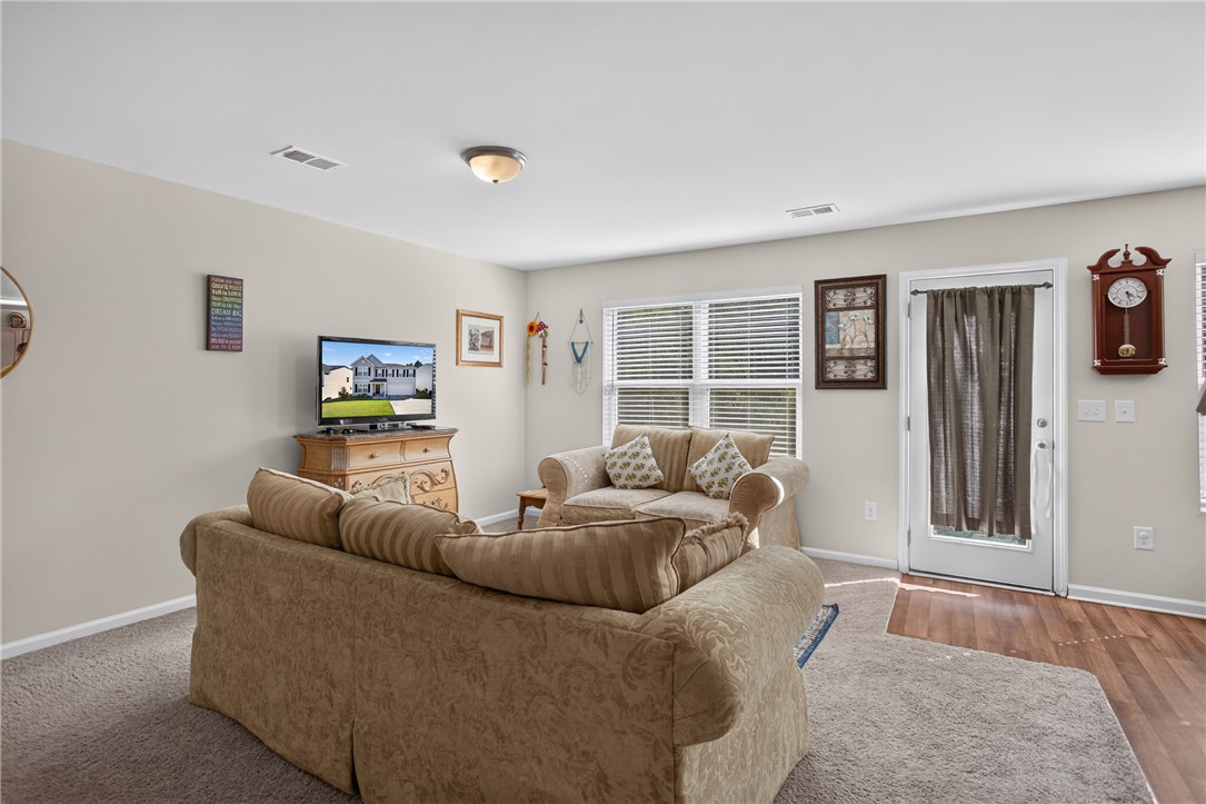 1081 Edenbrooke Circle Anderson, SC 29621 - Photo 5 of 46 A comfortable living space boasts a mix of wood and carpeted flooring, complemented by natural light from a large window and convenient exterior access.