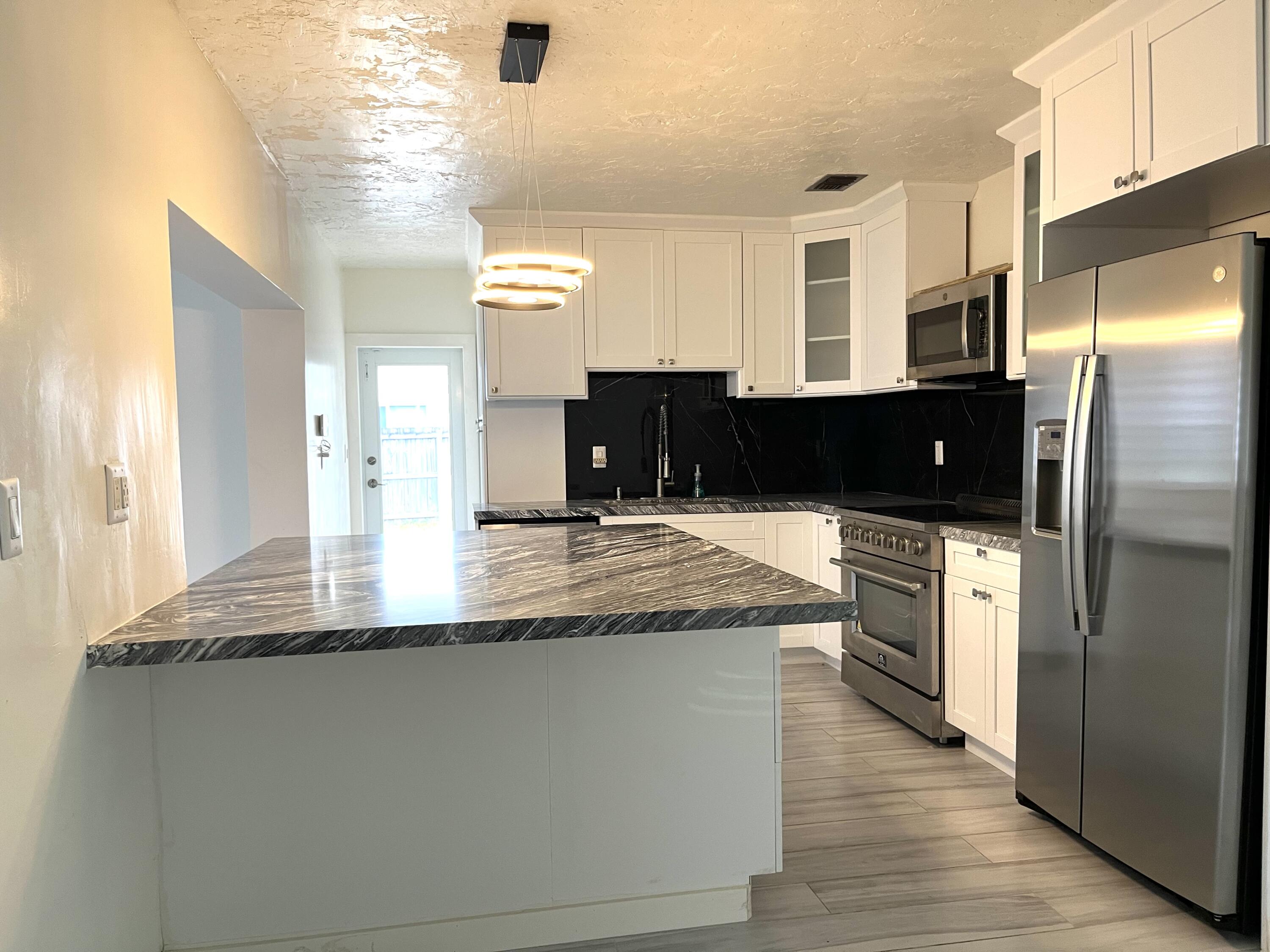 8760 Southwest 83rd Street Miami, FL 33173 - Photo 5 of 24 a kitchen with kitchen island granite countertop a refrigerator and a sink