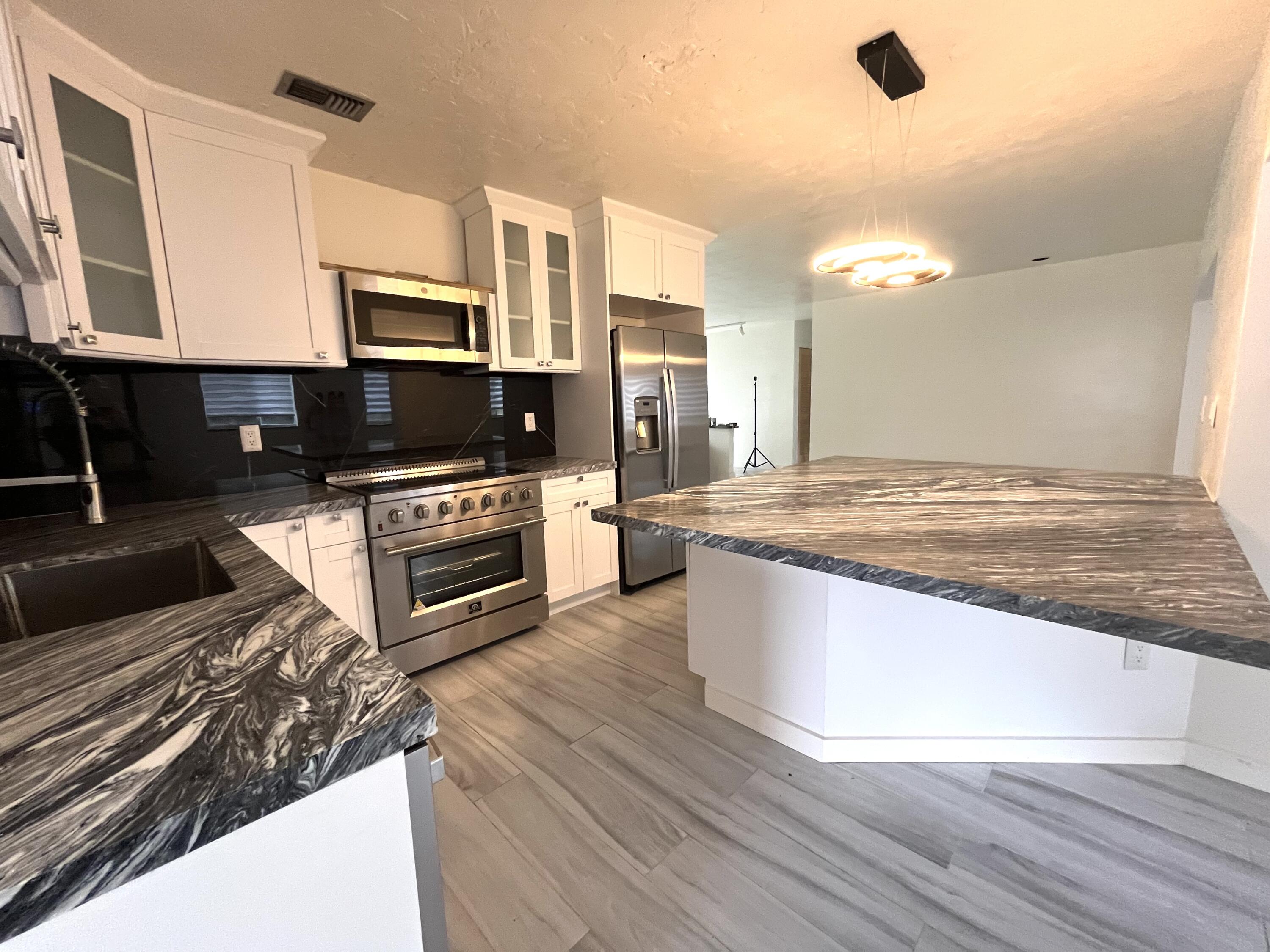 8760 Southwest 83rd Street Miami, FL 33173 - Photo 8 of 24 a kitchen with stainless steel appliances kitchen island granite countertop a stove a sink and a microwave
