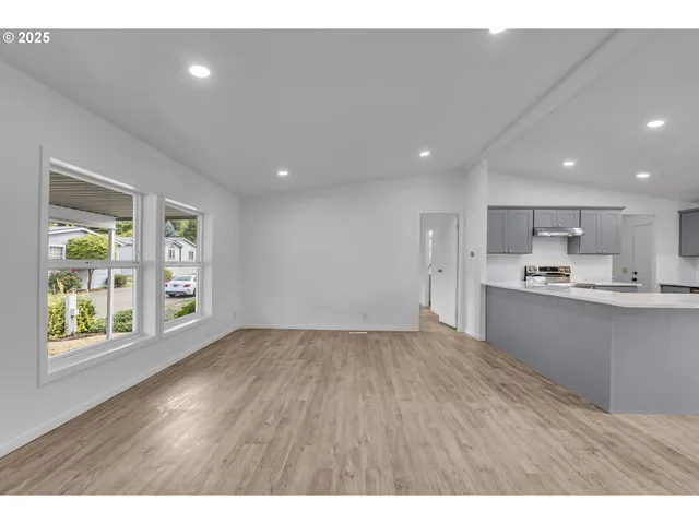 a view of kitchen and empty room with wooden floor