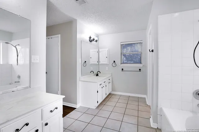 a spacious bathroom with a double vanity sink a mirror and a bathtub
