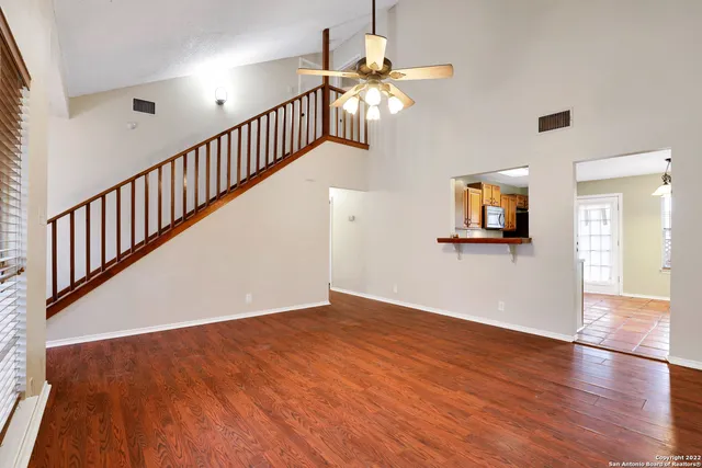 a view of an empty room with wooden floor and a chandelier