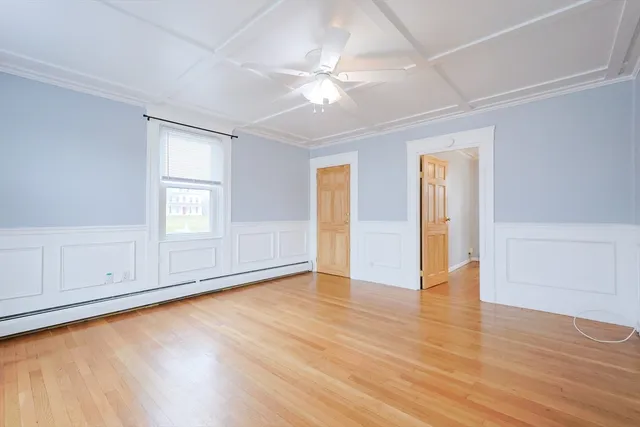 an empty room with wooden floor cabinet and windows