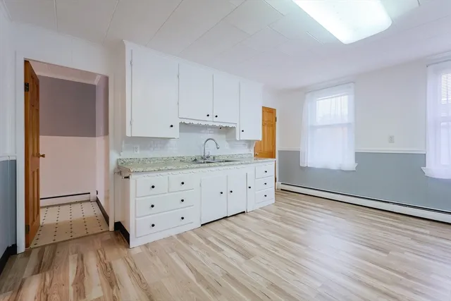 a kitchen with granite countertop a sink cabinets and wooden floor